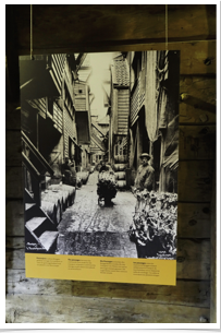 A photo showing dock workers loading goods in the alleyway between buildings.